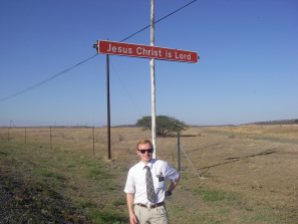 Elder Payne by a sign proclaiming Jesus